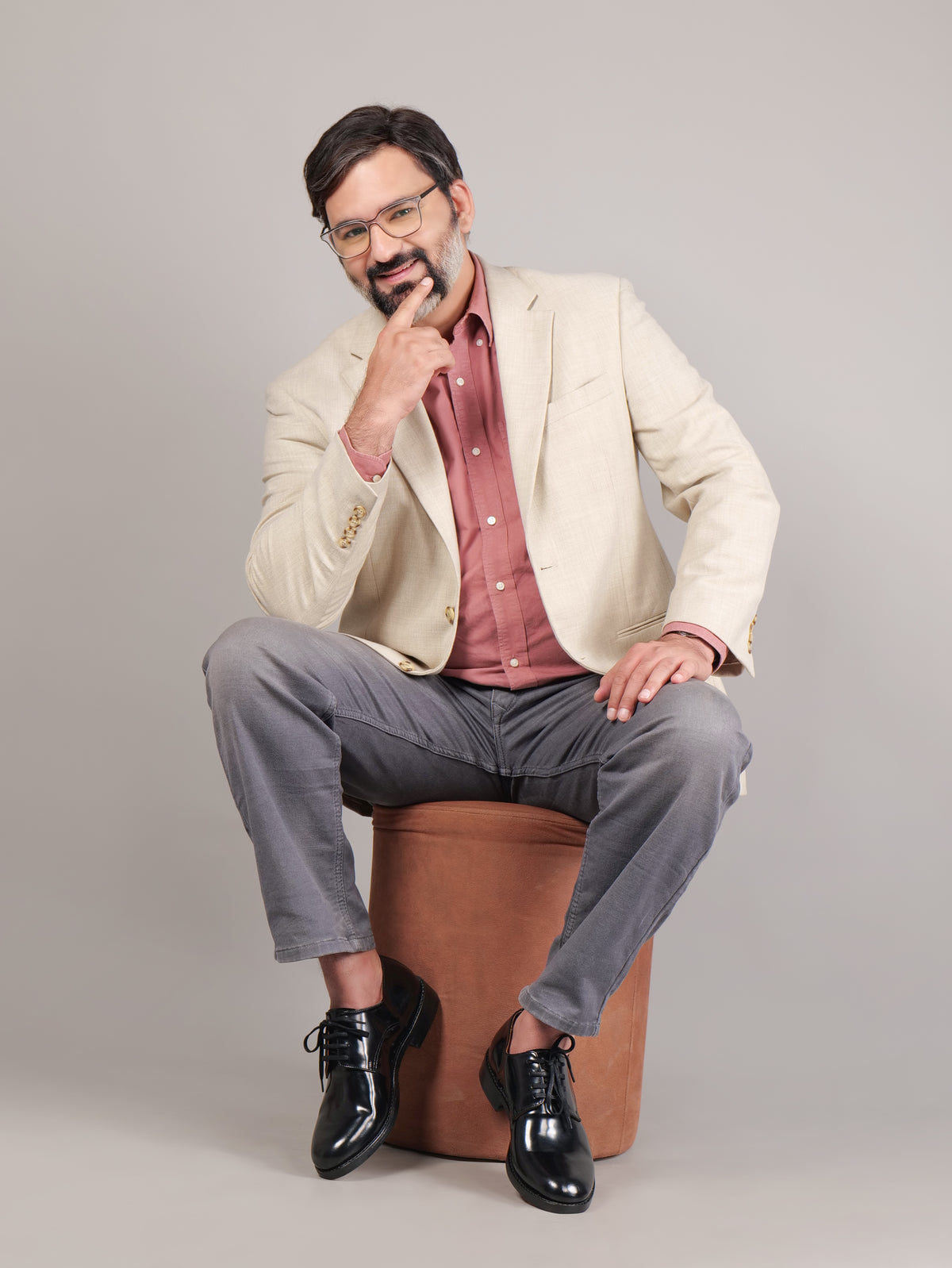 Black Blucher Goodyear welted leather shoes worn by a seated model in a reflective pose