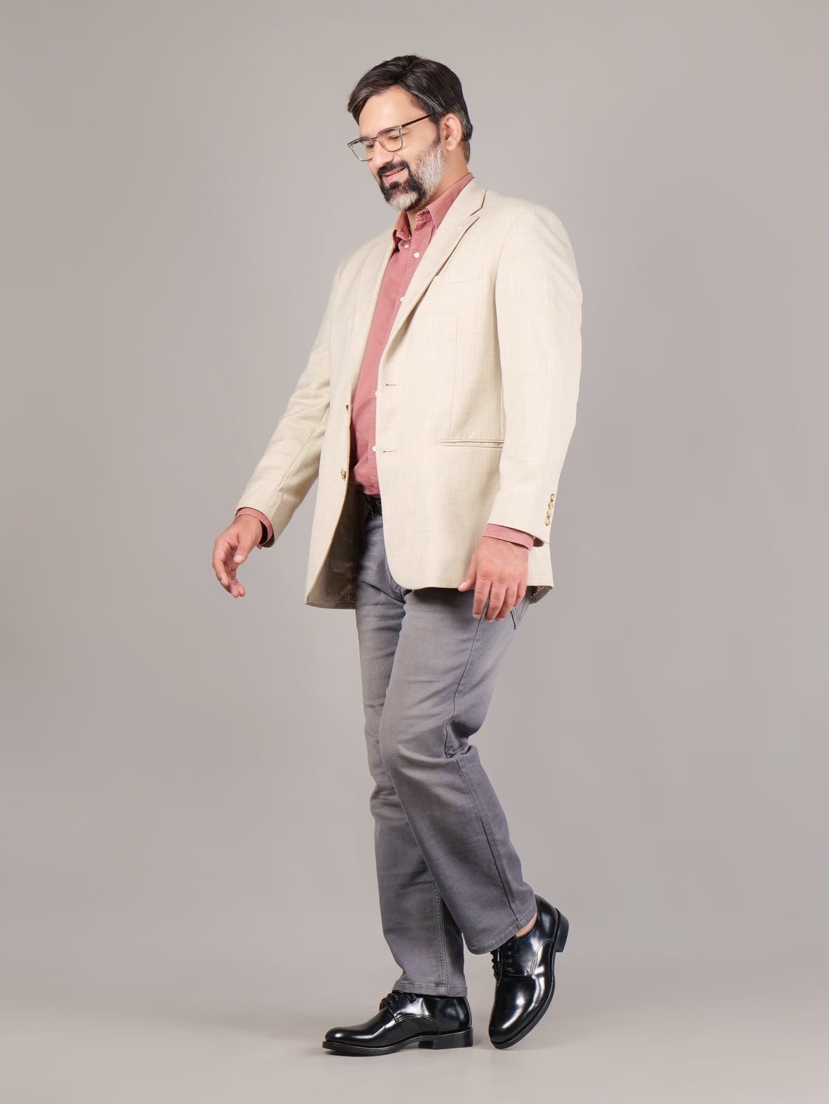 Male model walking in black Blucher Goodyear welted leather shoes against a gray background