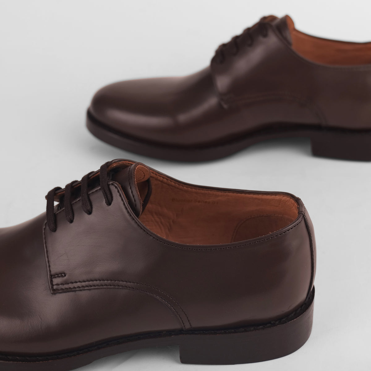Brown heel view of black Goodyear welted Blucher shoes with visible welt stitching