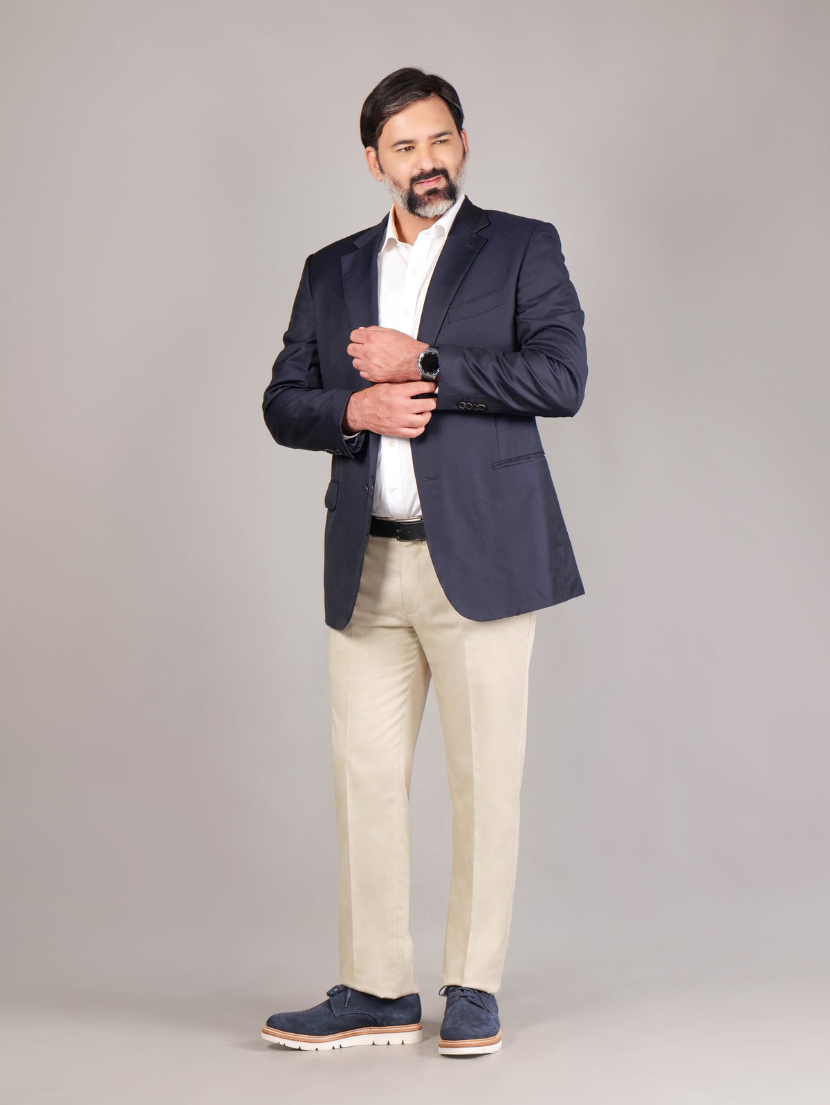 Male model wearing navy blue Blucher Suede shoes while standing against a beige background