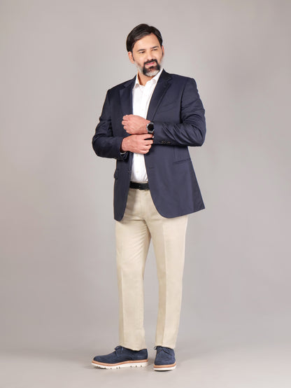 Male model wearing navy blue Blucher Suede shoes while standing against a beige background