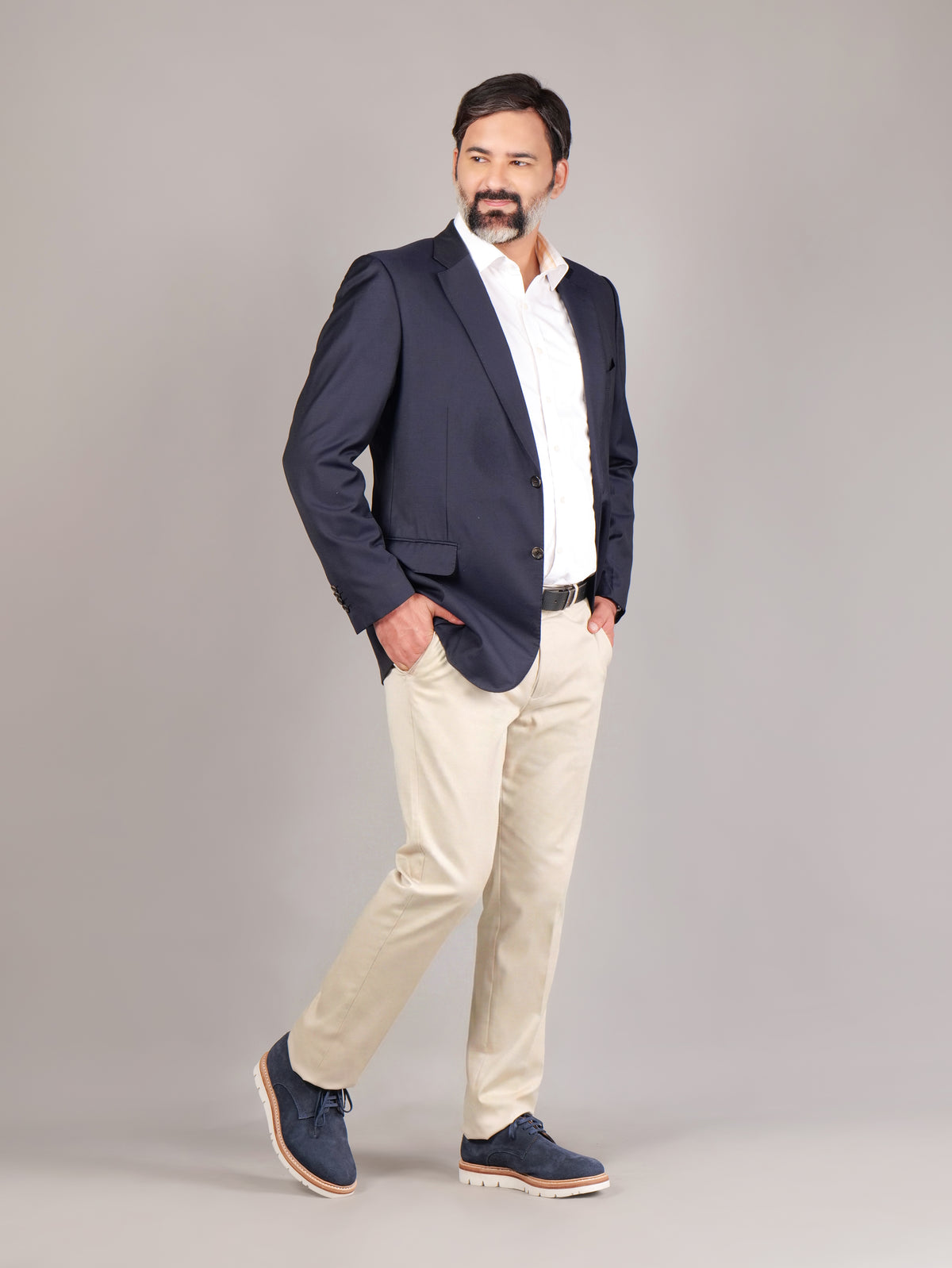 Male model wearing navy blue Blucher Suede shoes in a walking pose against a beige background